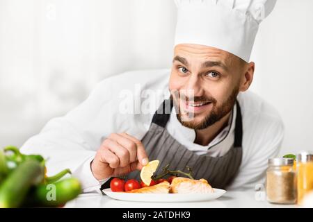 Happy Cook Man Plating Salmon Steak In Restaurant Kitchen Stock Photo