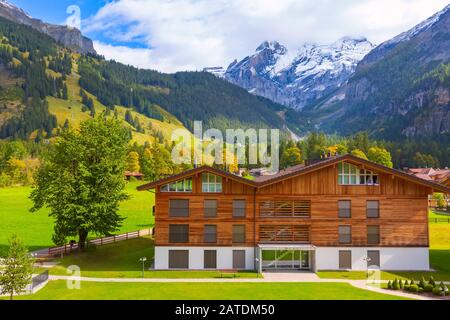 Wooden chalet in Kandersteg village, Canton Bern, Switzerland, Europe, Autumn trees and mountains panorama Stock Photo
