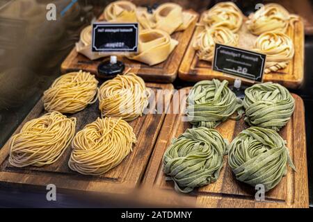 Closeup of raw fresh homemade green pasta tagliatelle. fresh italian traditional raw pasta on the counter in the storewith blurr price tags. Stock Photo