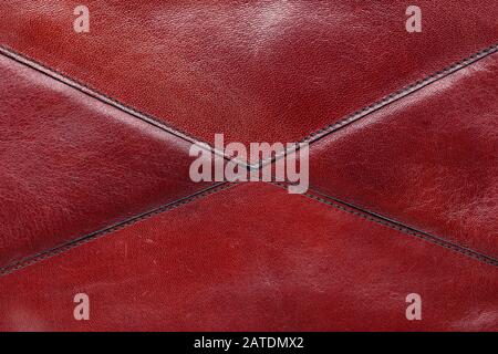 red leather background made from different pieces of leather. stitched by triangles. place for text. clearly visible texture of the skin and seams Stock Photo