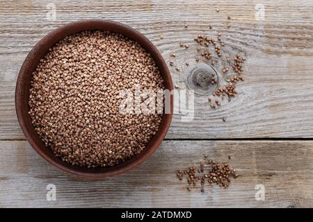 raw buckwheat in a clay plate on a wooden background. view from above. place for text Stock Photo