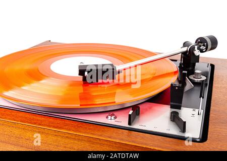 Vintage turntable with a red vinyl isolated on white. Wooden plinth. Retro audio equipment. Stock Photo