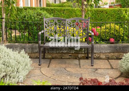 Empty two seat wrought iron bench in front garden of house, Edinburgh, Scotland Stock Photo
