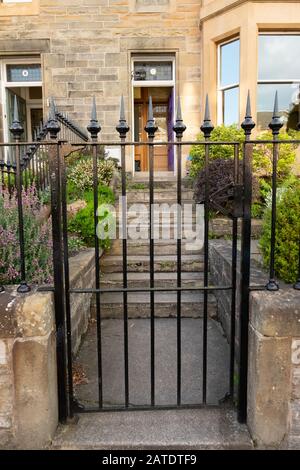 Wrought iron black gate with spikes, with steps and path to open front door of house, Edinburgh, Scotland Stock Photo