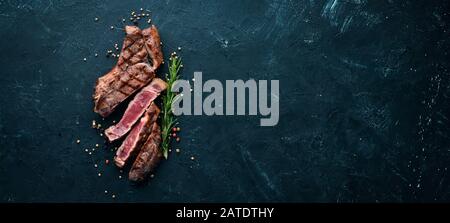 Veal steak on a bone on a black background. Free space for your text. Top view. Stock Photo