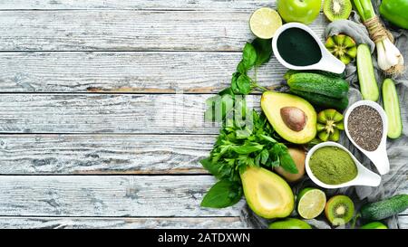 Fresh green vegetables in a rustic white background. Avocado, kiwi, onion, lime, parsley. Organic food. Rustic style. Top view. Free space for text. Stock Photo