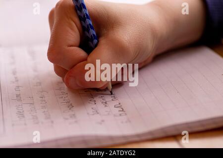 Child doing homework, writing lines and sentences with pencil Stock Photo