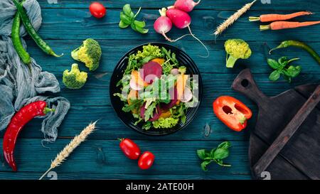 Salad of fresh beets, tomatoes, and lettuce. Healthy food. On a blue wooden table. Top view. Free space for text. Stock Photo
