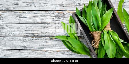 Fresh young wild garlic leaves on a white wooden background. Top view. Free space for your text. Stock Photo