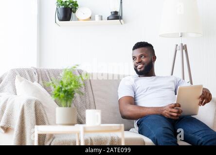 Cheerful african man with portable pc looking aside Stock Photo
