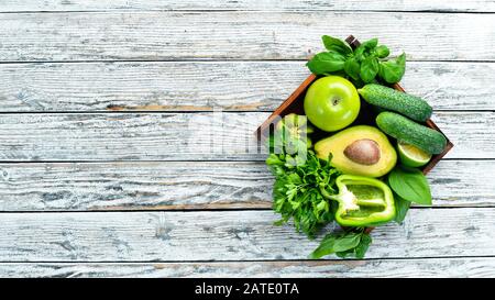 Fresh organic green fruits and vegetables. Avocado, kiwi, onion, lime, parsley. Organic food. Rustic style. Top view. Free space for text. Stock Photo