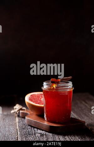 jar with grapefruit jam on an old wooden background in dark style. Stock Photo