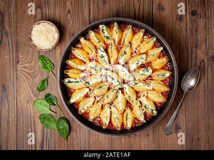 Stuffed pasta shells with spinach and ricotta on an old wooden background. view from above. Stock Photo