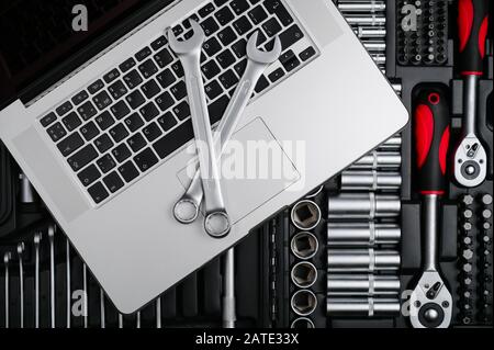 silver chrome wrench and spanner lying on laptop on toolbox with pro tools Stock Photo
