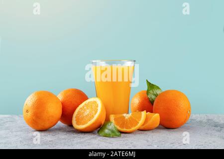 Fresh orange juice glass and oranges on light blue background Stock Photo