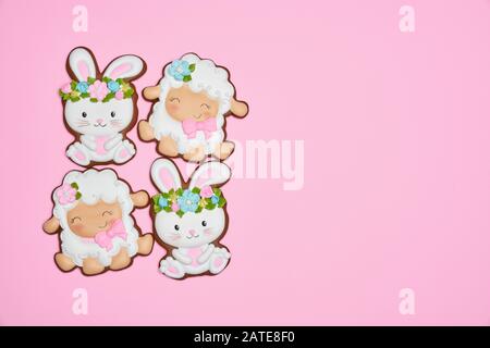 From above view of glazed cookies isolated on pink background. Easter ginger cookies in shape of two bunnies in wreaths and two sheep making square. Spring and easter holidays concept. Stock Photo