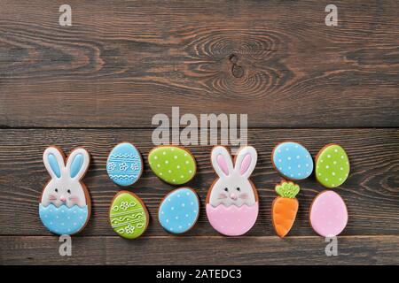 From above view of colorful ginger glazed cookies isolated on wooden background. Homemade lovely delicious pastry in shape of easter bunnies, eggs and carrot in row. Concept of holiday. Stock Photo
