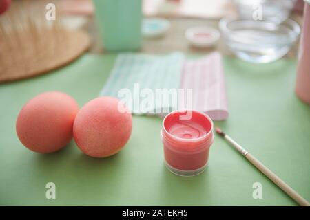 Close up of beautiful pastel pink eggs on table in art studio next to paint brush, Ester decorations concept, copy space Stock Photo