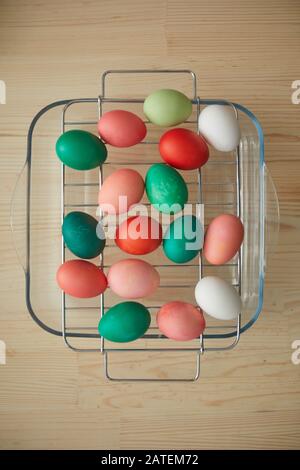 Above view background of red and green hand-painted Easter eggs on drying rack over wooden table in art studio, copy space Stock Photo