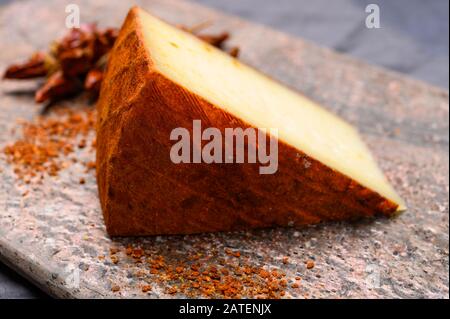 Cheese collection, piece of Spanish manchego cheese made from cow milk with red paprika close up Stock Photo