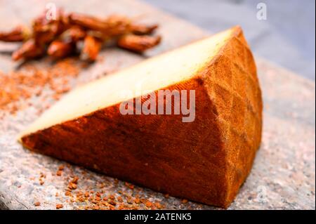 Cheese collection, piece of Spanish manchego cheese made from cow milk with red paprika close up Stock Photo