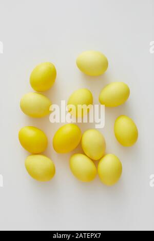 Top view of pastel yellow Easter eggs arraigned in minimal composition on white background, copy space Stock Photo