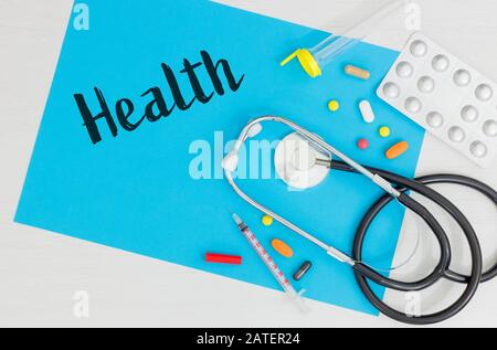 Spilled medicine that with a stethoscope, laboratory vial, syringe on a blue card with the inscription 'Health' Place for an inscription Stock Photo