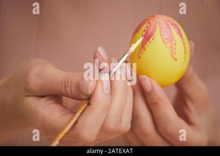 Extreme close up of female hands painting intricate design on Easter egg, copy space Stock Photo