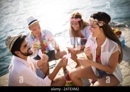 Group of creative friends sitting at wooden table. People having fun while playing board game. Stock Photo