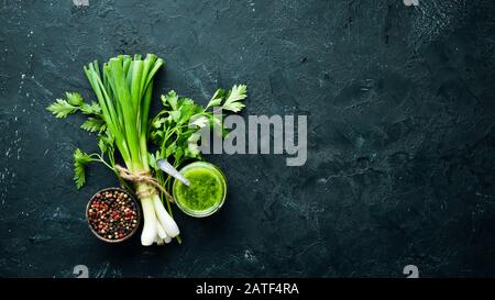Green parsley sauce, olive oil and spices. Ingredients for chimichurri sauce. On a black background. Top view. free space for your text. Stock Photo