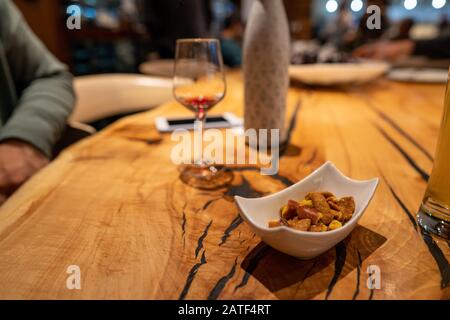 Bowl of nuts next to empty wine glass on wooden restaurant table Stock Photo