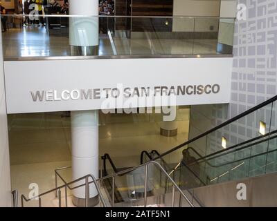 Welcome to San Francisco sign as travelers walk down stairs at San Francisco International Airport SFO Stock Photo