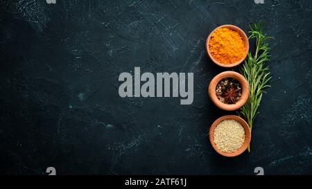 Colored spices on a black stone background. Free space for your text. Top view. Stock Photo