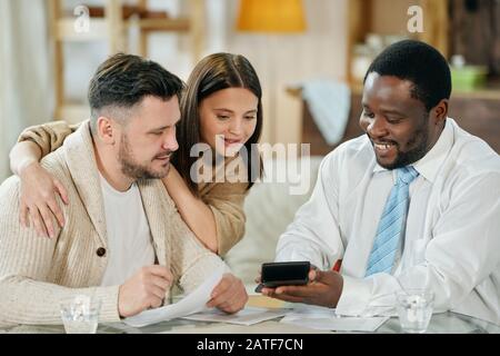 Content man advising young couple on home loan Stock Photo