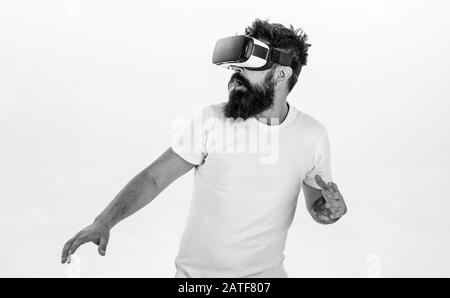 Hipster on scared face exploring virtual reality with modern gadget. Man with beard in VR glasses run away , white background. VR game concept. Guy with head mounted display run in virtual reality. Stock Photo
