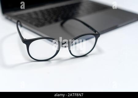 protective glasses on an empty desk with blurred computer screen on background Closeup Stock Photo