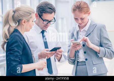 Business people with mobile phones surfing the net at break in office Stock Photo