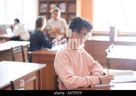 Youthful clever student of college looking at you through eyeglasses Stock Photo