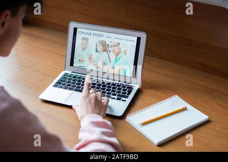 Laptop with image of schoolkids on screen and college student touching key Stock Photo