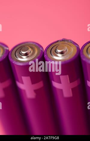 Four small batteries on a pink table. Stock Photo