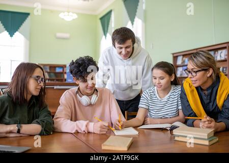Large group of teenage learners preparing for seminar in college library Stock Photo