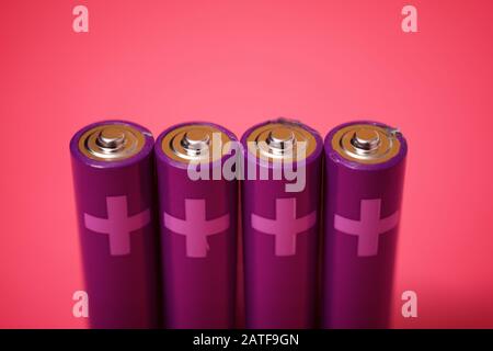 Four small batteries on a pink table. Stock Photo