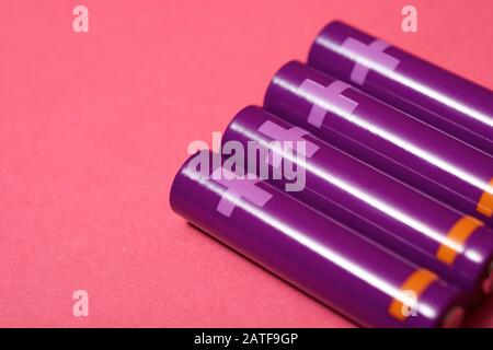 Four small batteries on a pink table. Stock Photo