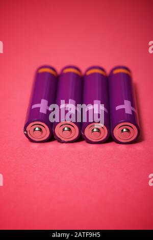 Four small batteries on a pink table. Stock Photo