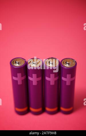 Four small batteries on a pink table. Stock Photo