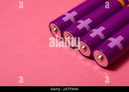 Four small batteries on a pink table. Stock Photo