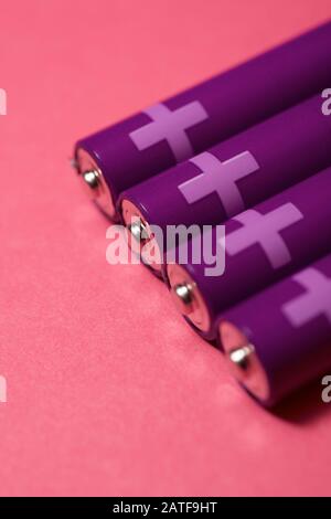 Four small batteries on a pink table. Stock Photo