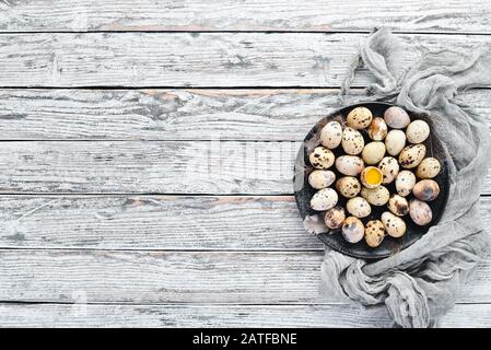 Quail eggs in a black plate. On the old background. Top view. Free copy space. Stock Photo