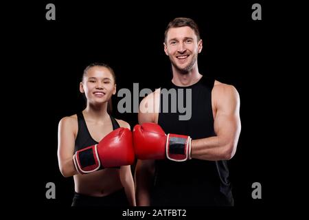 Happy man and woman in activewear touching each other hands in boxing gloves Stock Photo
