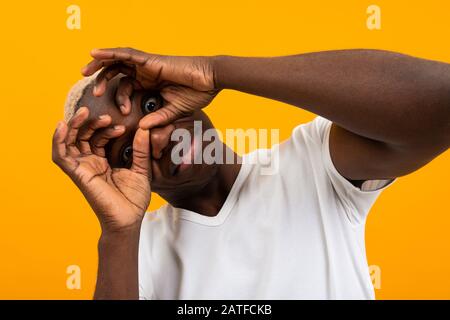 surprised black african young man covers his face with his hands and bulges his eyes. Stock Photo